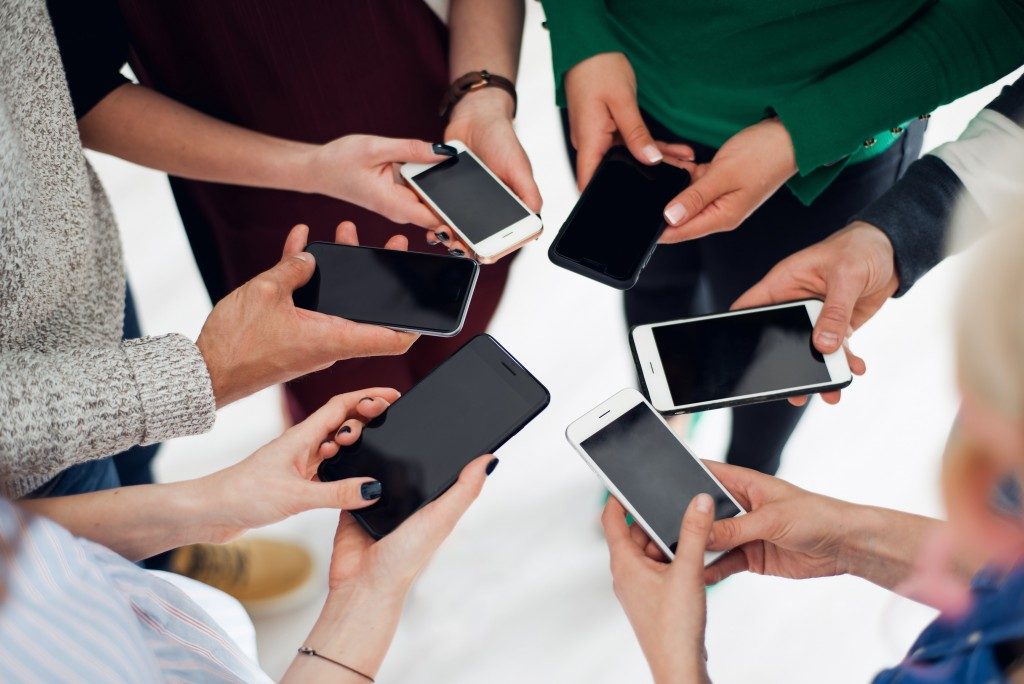 group of colleagues using their smartphones in a huddle
