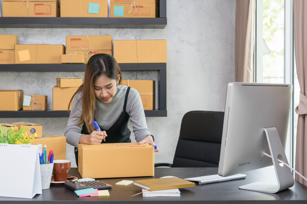 a person writing on a box in front of her computer