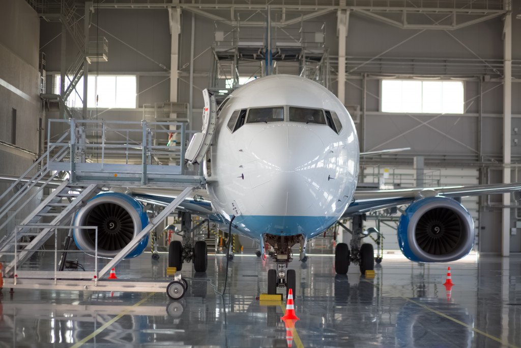 An airplane parked in a warehouse with a ladder