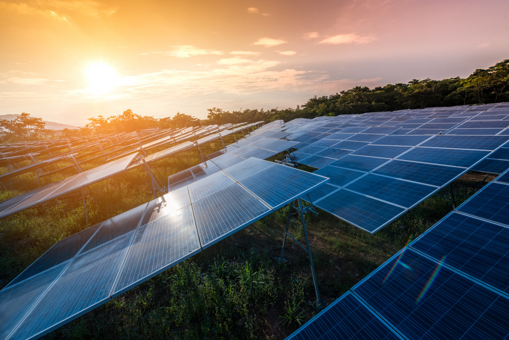 a bunch of solar panels and the sun in the backdrop