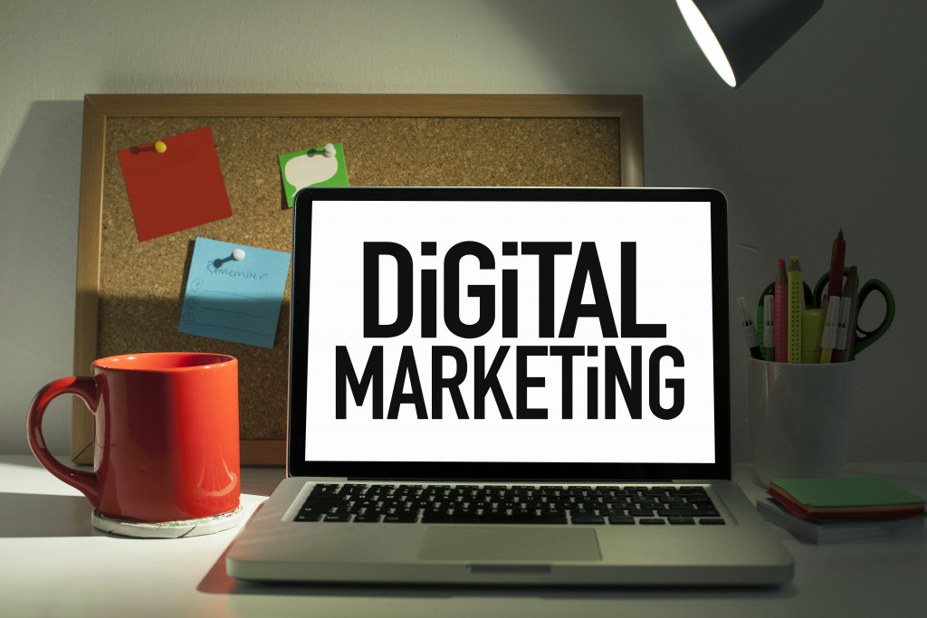 digital marketing concept flashed in laptop in office table with coffee mug, bulletin board, and pens